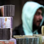 أكوام من الأوراق النقدية بالليرة السورية في كشك لصراف العملات في سوق بمدينة منبج في محافظة حلب شمال سوريا في 4 يناير/كانون الثاني 2025